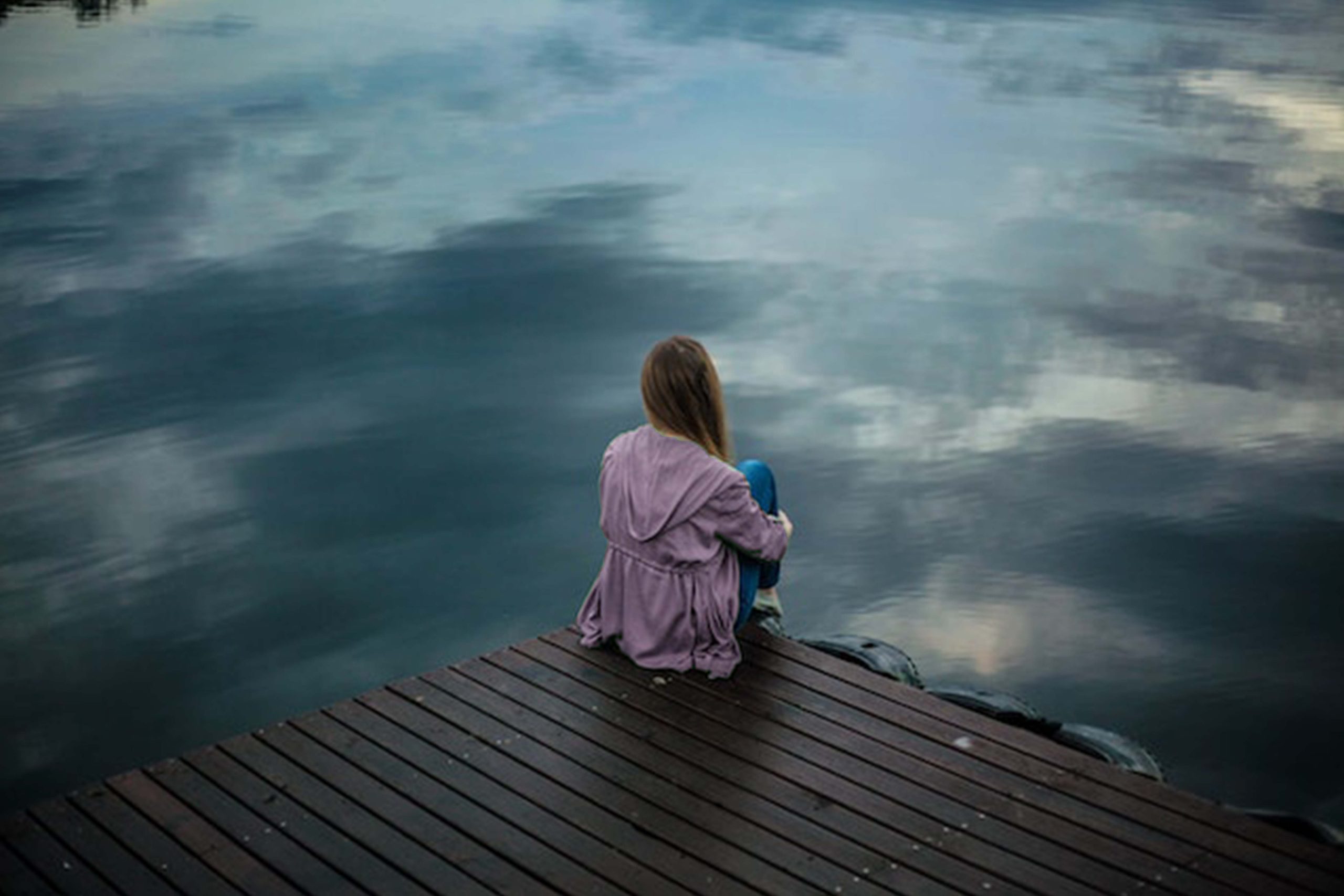A girl sitting on a pier feeling empty